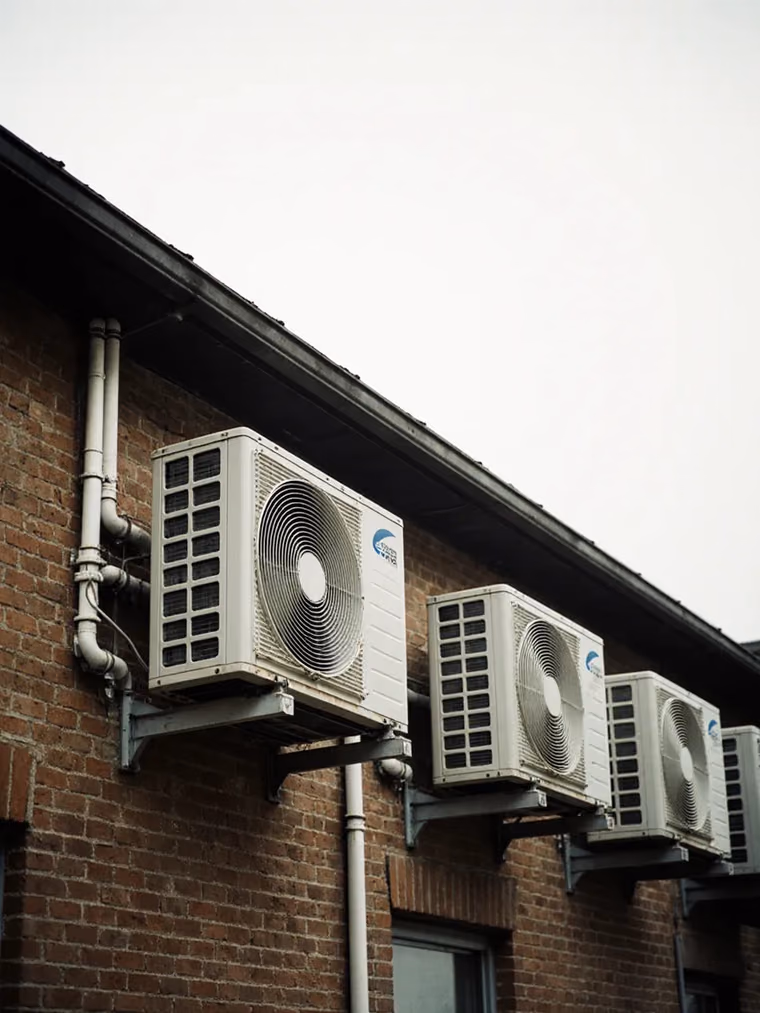 Heat pump condensing units mounted on the wall of a brick building