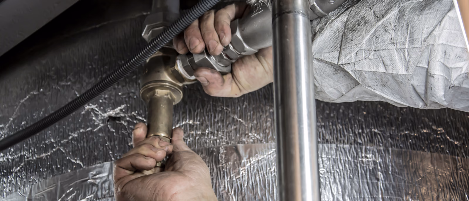 Hands fitting pipework with a wrench